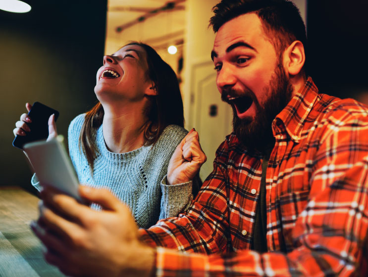 Excited male and female hipsters rejoice in winning an internet lottery made bets on website on modern smartphone.Happy couple in love celebrating victory in online competitions enjoying success