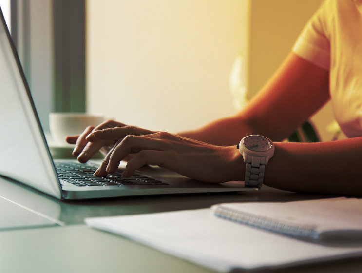 Woman's hands typing on laptop at workplace.